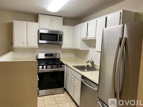 A kitchen with white cabinets and a stainless steel refrigerator.