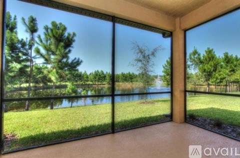 A room with a view of a lake and trees through large windows.