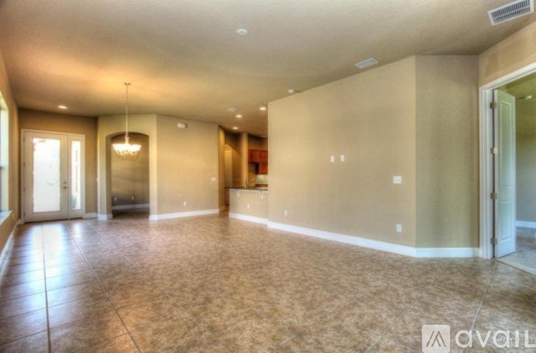 A spacious room with a tiled floor and a chandelier hanging from the ceiling.