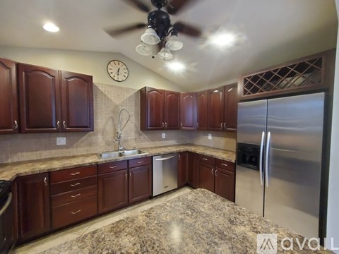 A kitchen with brown cabinets and a stainless steel refrigerator.