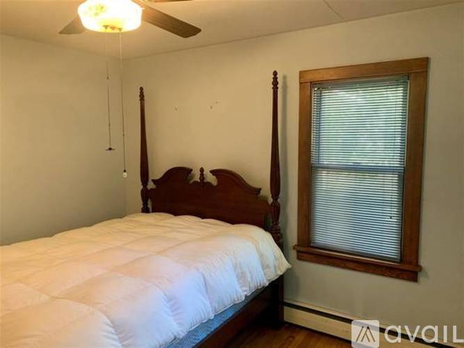 A bedroom with a bed, window, and a ceiling fan.