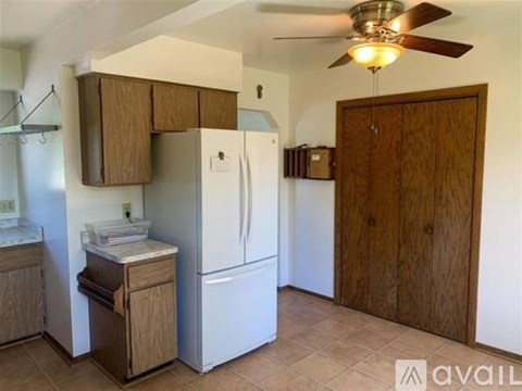 A kitchen with a white refrigerator and wooden cabinets.