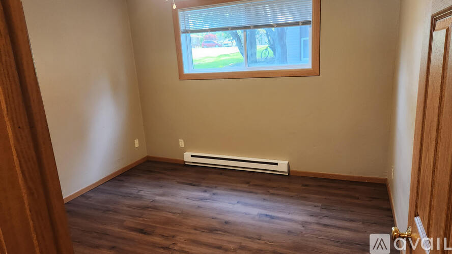 A room with a window and a heater on the floor.