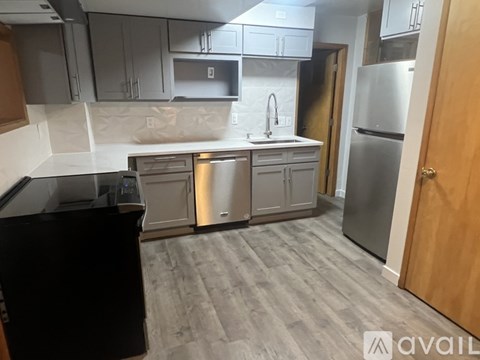 A kitchen with a black counter top and stainless steel appliances.