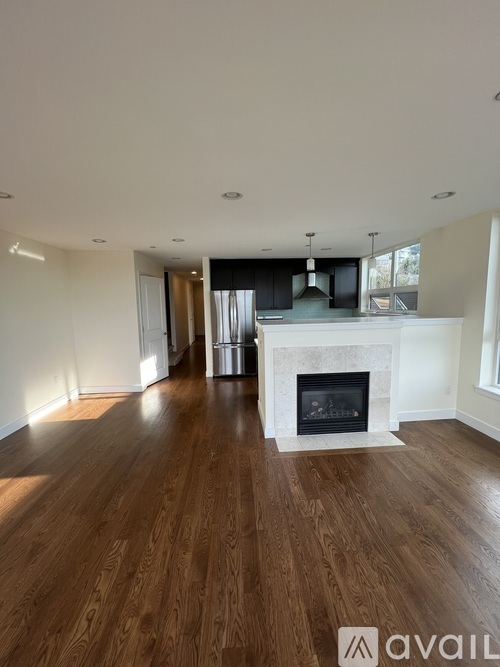 A spacious living room with a fireplace and wooden floors.