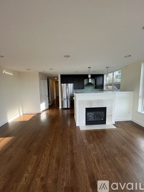 A spacious living room with a fireplace and wooden floors.