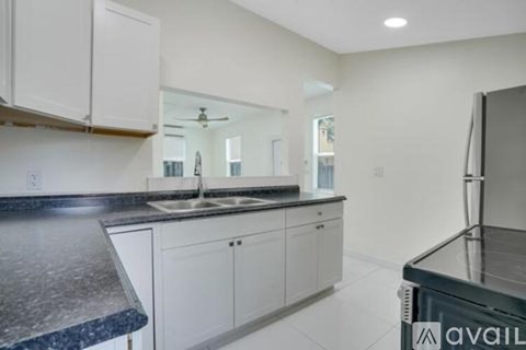 A kitchen with white cabinets and a black countertop.