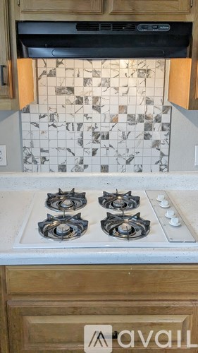 A kitchen with a stove top and a backsplash with tiles.