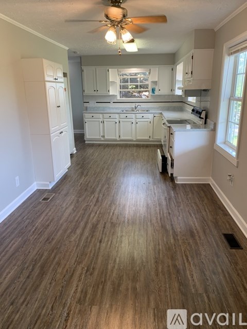 A kitchen with white cabinets and a wooden floor.