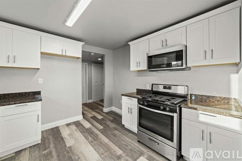 A kitchen with white cabinets and a granite countertop.