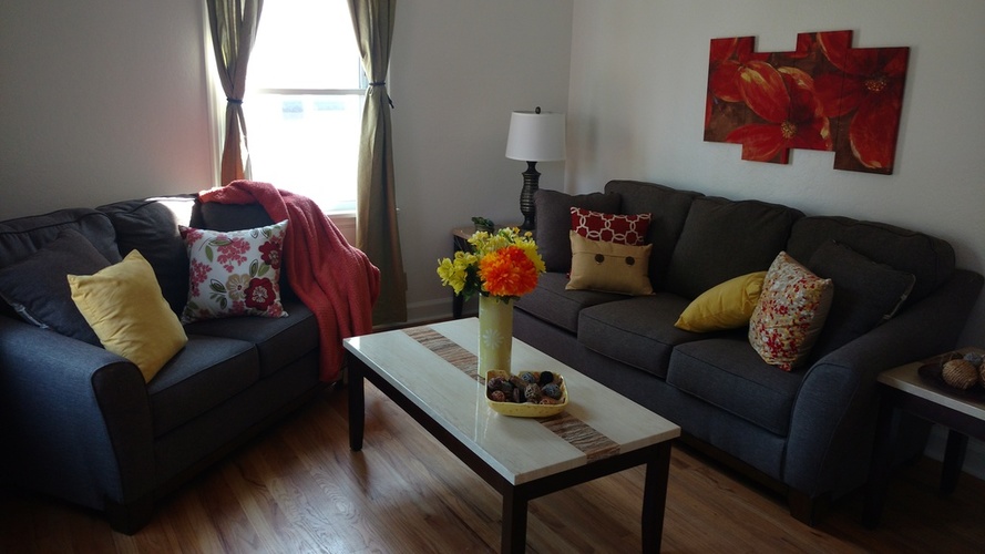 A living room with a grey couch, a coffee table, and a painting on the wall.