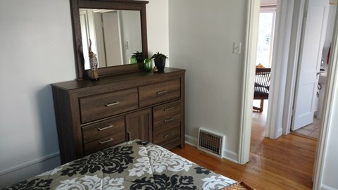 A bedroom with a bed, dresser, and mirror.