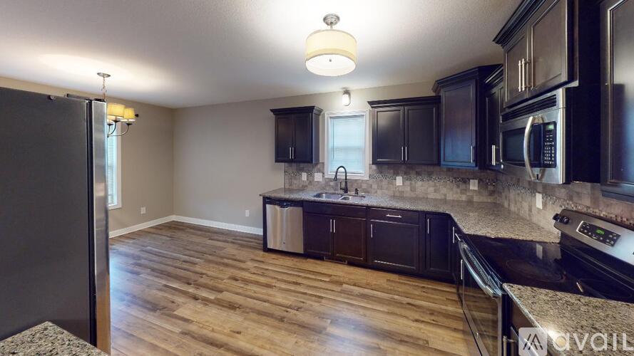 A kitchen with dark wood cabinets and a black refrigerator.