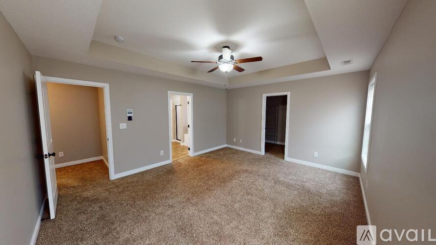 A spacious room with a ceiling fan and carpeted floor.