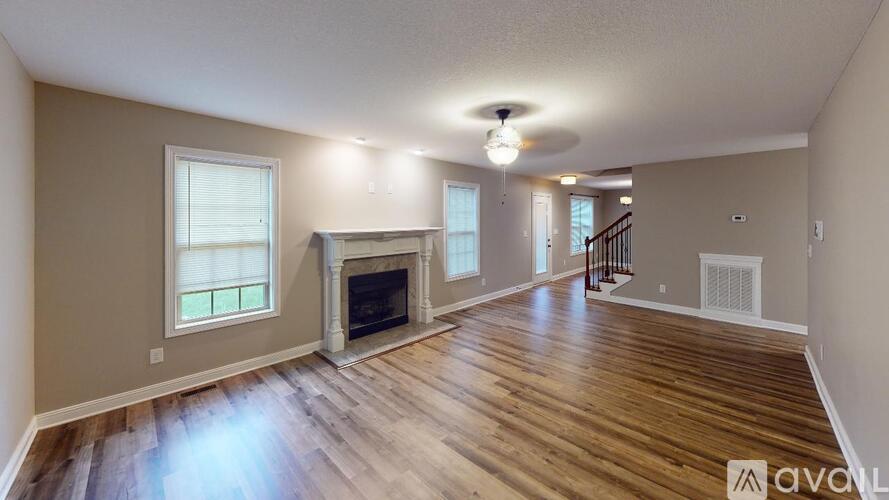 A spacious living room with wood flooring and a fireplace.