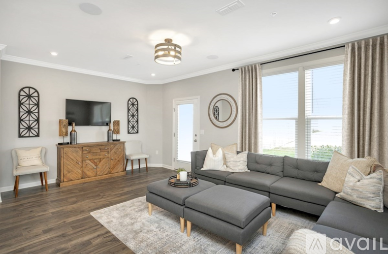 A living room with a grey sofa, a wooden cabinet, a TV, and a rug.