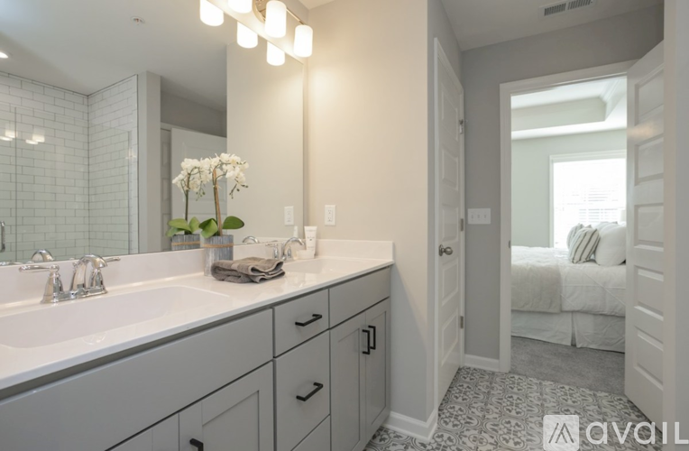 A bathroom with a sink, mirror, and a bedroom in the background.
