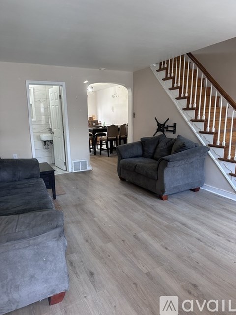 A living room with a grey couch and a wooden staircase.