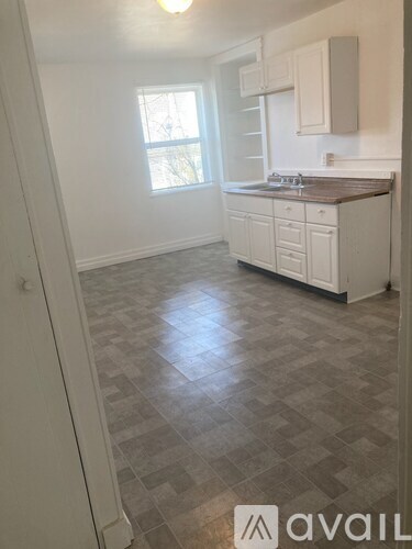 A kitchen with white cabinets and a tiled floor.