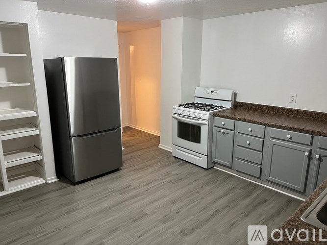 A kitchen with a stainless steel refrigerator, a white stove, and a white oven.
