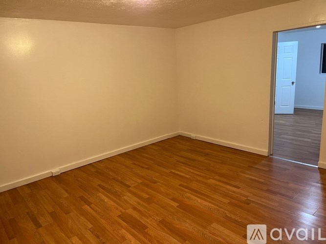 Empty room with wooden flooring and white walls.