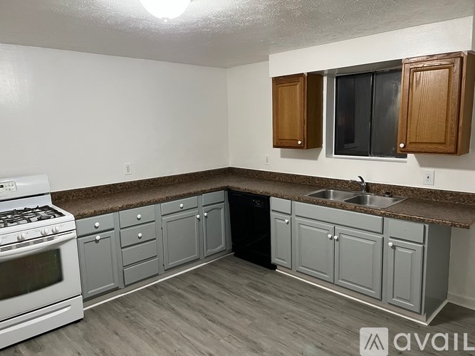 A kitchen with a white stove and grey cabinets.