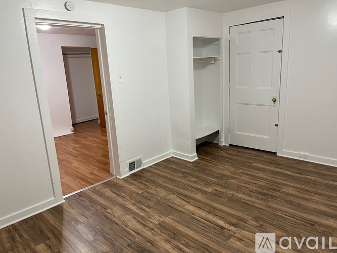 A room with a white door and a wooden floor.