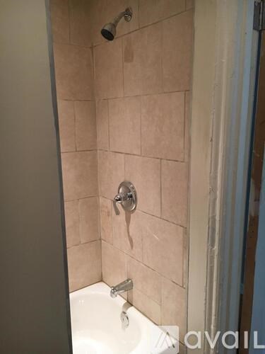 A shower with a white tub and a wall of tiles.