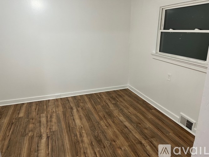 A room with wooden flooring and a window.