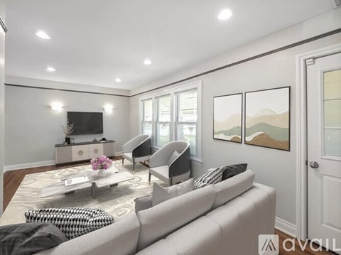 A living room with a grey sofa, a coffee table with a vase of flowers, a television, and a painting on the wall.