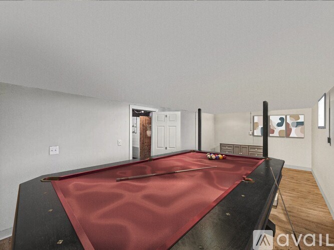 A pool table with a red cloth is in the middle of the room.