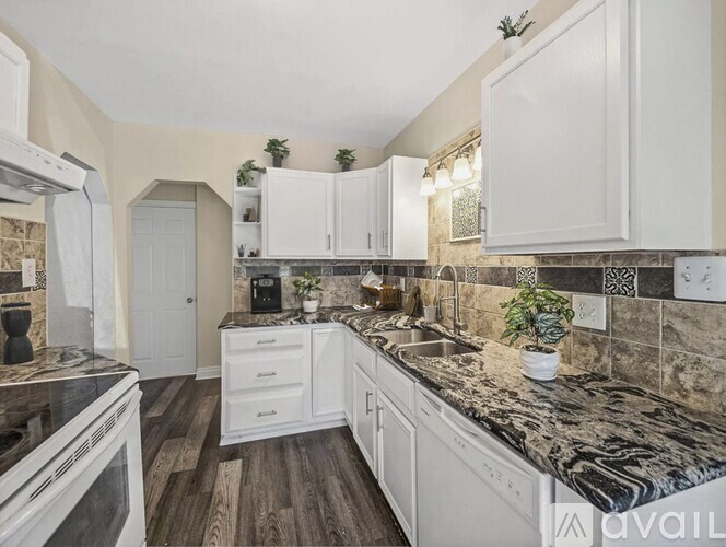 A kitchen with white cabinets and a marble countertop.
