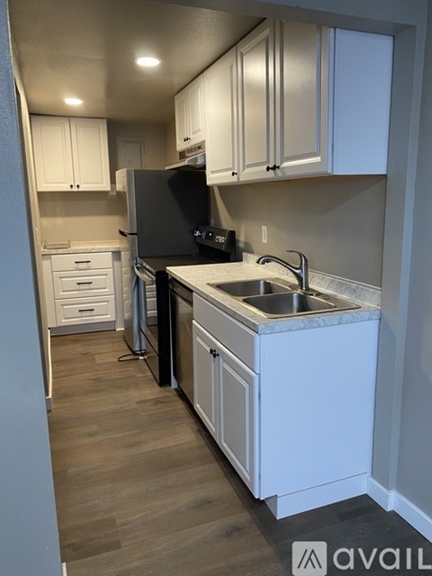 A kitchen with white cabinets and a black refrigerator.