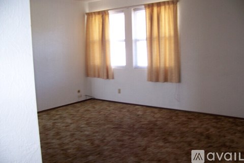 A room with a carpeted floor and a window with curtains.