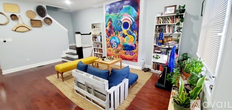 A living room with a blue couch and a large painting on the wall.