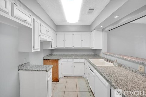 A kitchen with white cabinets and a granite countertop.
