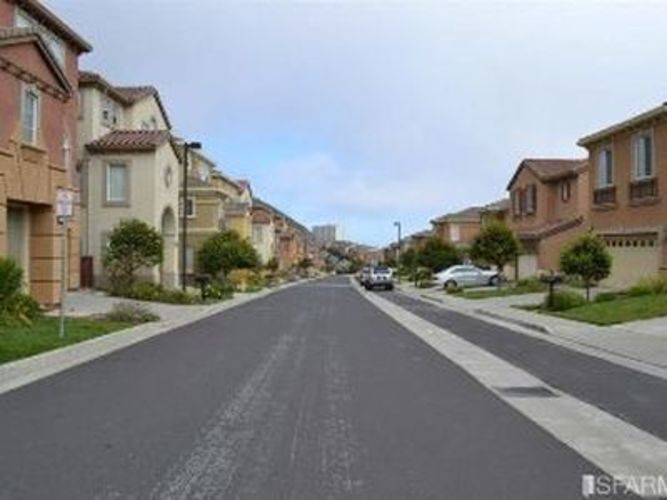 A street with houses on both sides and cars parked on the side.