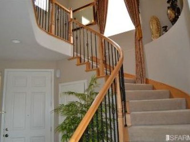 A staircase with a wooden handrail and beige carpeted steps.
