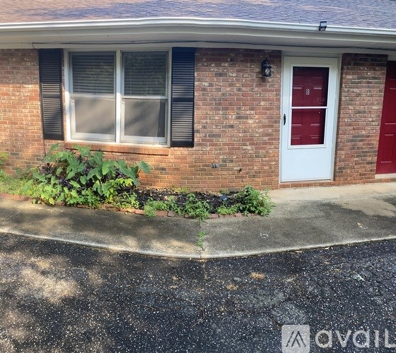 A red door is on the right side of a brick house.