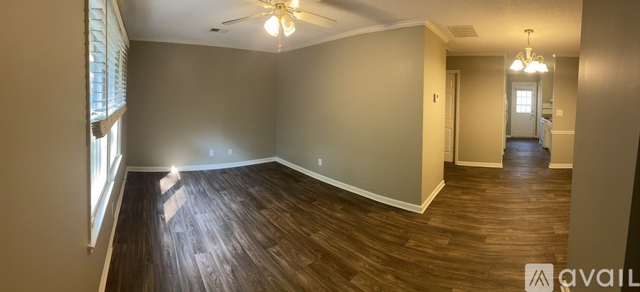 A spacious room with wood flooring and a ceiling fan.