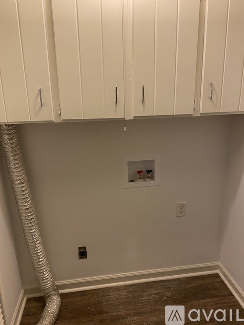 A room with white cabinets and a white wall with a pipe.
