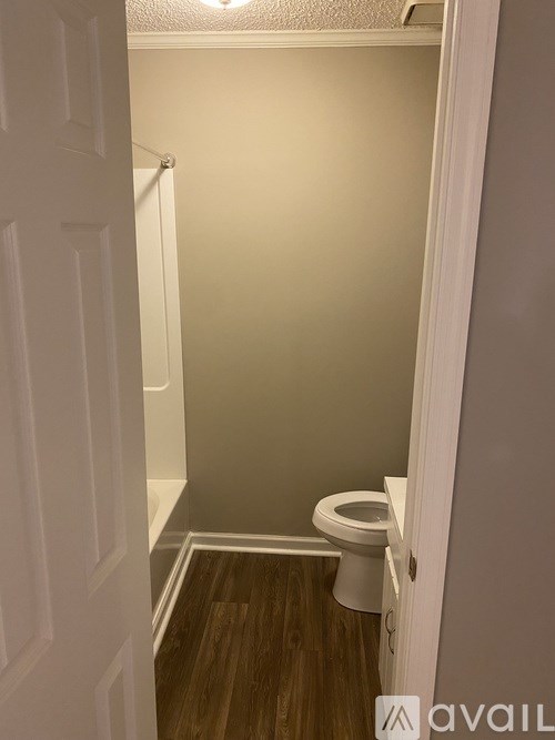 A small bathroom with a toilet and wooden floor.