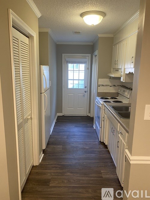 A kitchen with white cabinets and a wooden floor.