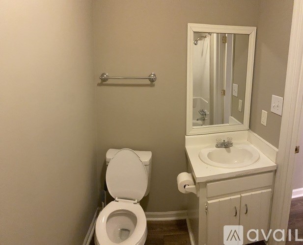 A bathroom with a toilet, sink, and mirror.