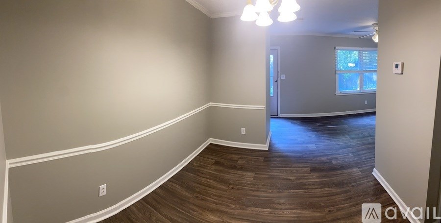 A room with wooden flooring and a doorway leading to another room.