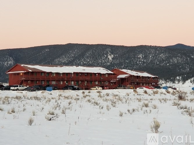 A large red building with a white roof is surrounded by snow.