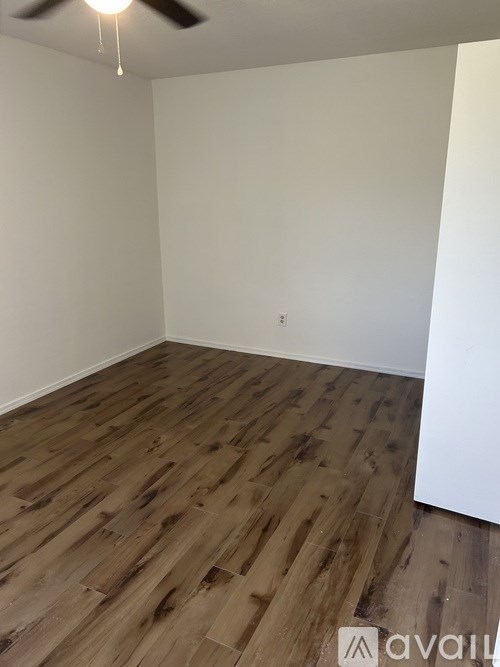 A room with wooden flooring and a ceiling fan.