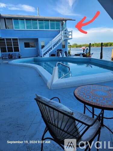 A patio with a table and chairs overlooking a pool and dock.