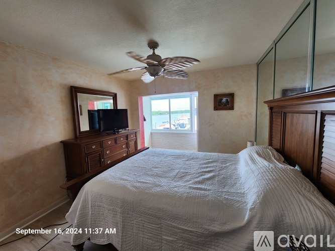 A bedroom with a bed, dresser, and ceiling fan.