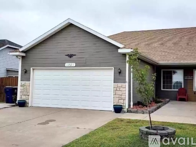 A house with a garage door and a tree in front.